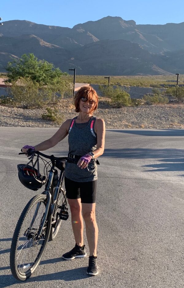 A woman standing next to her bike on the side of a road.