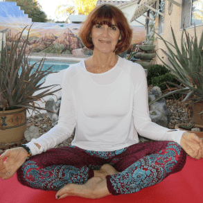 A woman sitting on the ground in a yoga pose.