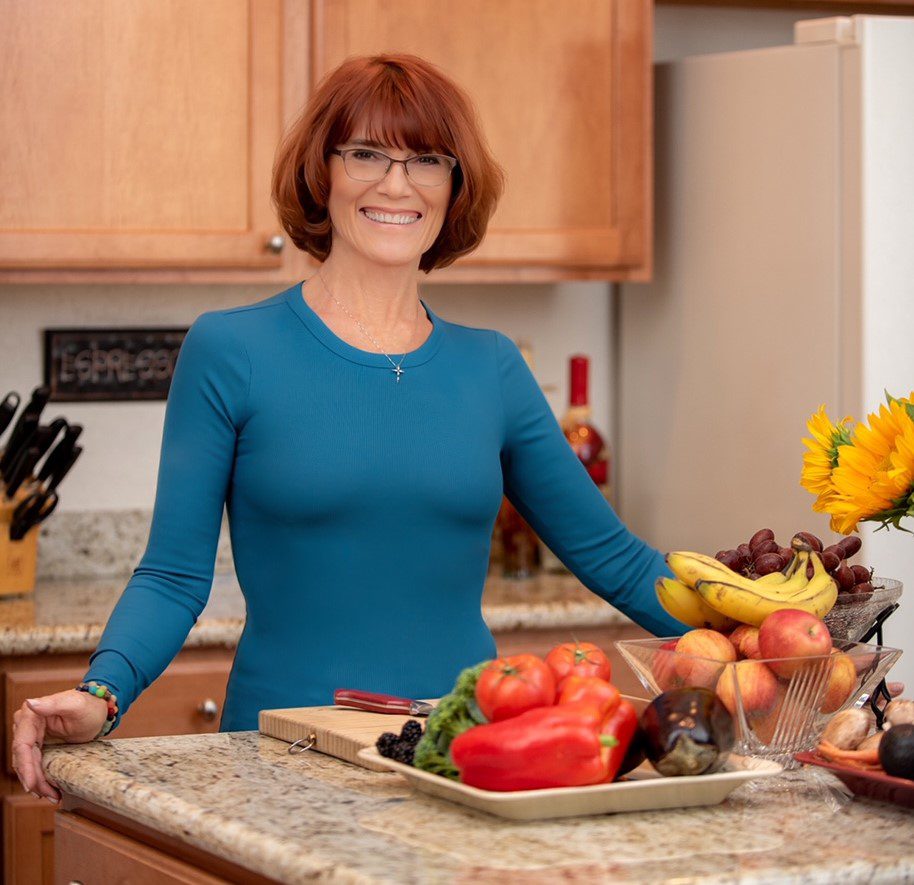 A woman standing in the kitchen with some fruit.