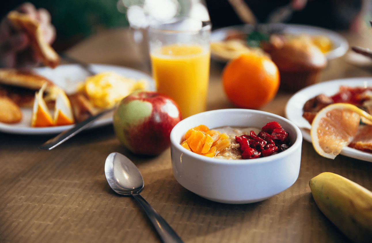 A bowl of cereal with fruit and orange juice.
